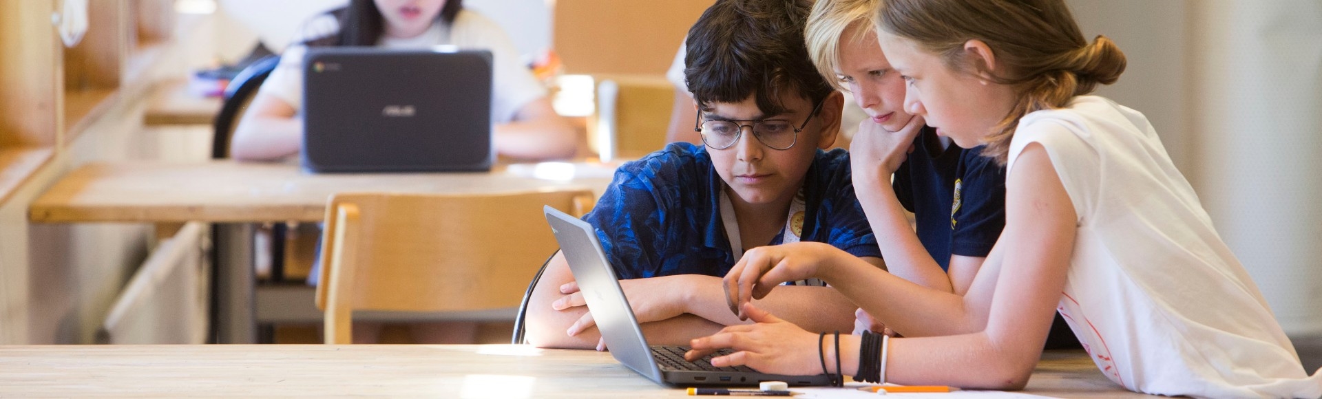 Tre elever jobbar tillsammans på en laptop